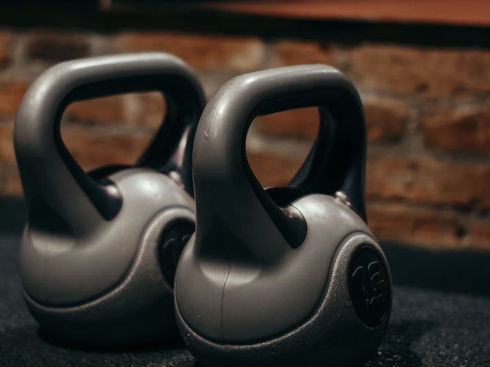 Δύο kettlebells στο πάτωμα ενός γυμναστηρίου, μπροστά σε τοίχο από τούβλα